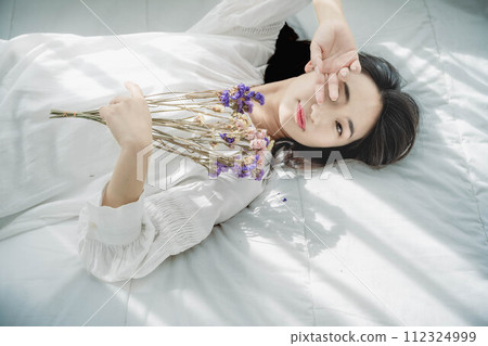 A woman lying on a bed with flowers A woman lying on a bed with flowers 112324999