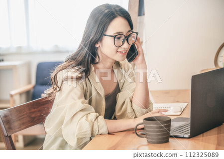 A young woman wearing glasses and teleworking A young woman wearing glasses and teleworking 112325089