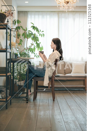 A woman working with a computer and a book in her room 112325168