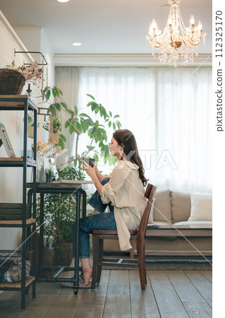 A woman working with a computer and a book in her room A woman working with a computer and a book in her room 112325170