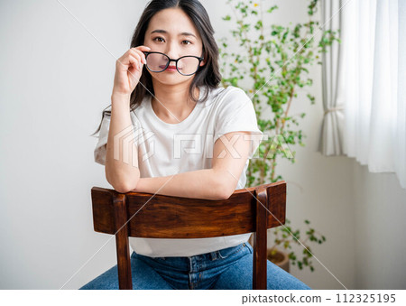 A woman who looks good in glasses sitting on a chair A woman who looks good in glasses sitting on a chair 112325195