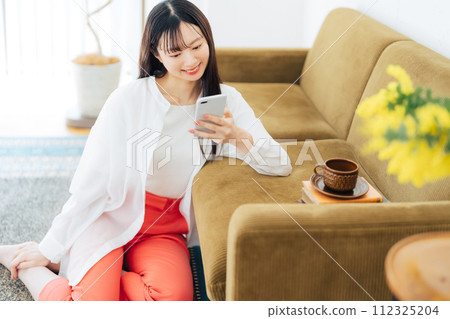 Young woman looking at her smartphone in the living room 112325204