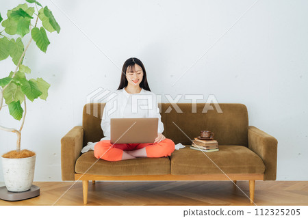 Woman using a computer on the sofa Woman using a computer on the sofa 112325205