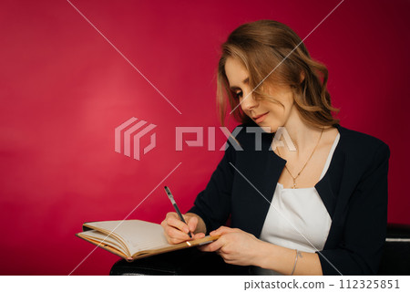 Image of smiling beautiful woman writing down notes while sitting 112325851