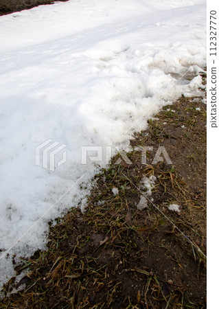 Melting snow on side of road by curb Melting snow on side of road by curb 112327770