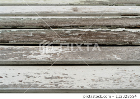 Close-up view of the old wooden building boards chipped and peeling painted white from old paint. Close-up view of the old wooden building boards chipped and peeling painted white from old paint. 112328554
