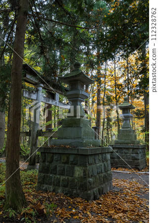 日本：青森縣十和田市奧瀨十和田安谷十和田湖畔十和田神社的燈籠和雪松林立的神社參道上的秋葉 112328762