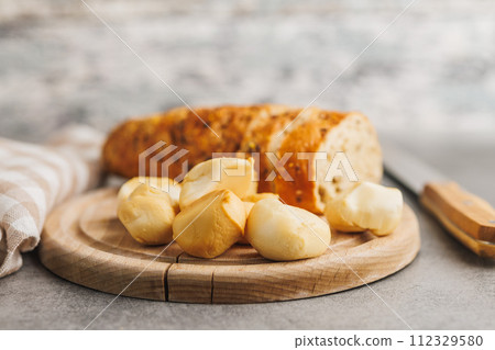 Smoked mini scamorza cheese. Traditional italian cheese on cutting board on kitchen table. Smoked mini scamorza cheese. Traditional italian cheese on cutting board on kitchen table. 112329580