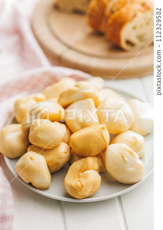 Smoked mini scamorza cheese. Traditional italian cheese on plate on white table. 112329582