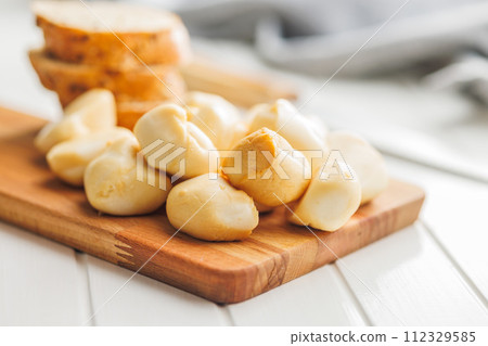 Smoked mini scamorza cheese. Traditional italian cheese on cutting board on white table. Smoked mini scamorza cheese. Traditional italian cheese on cutting board on white table. 112329585