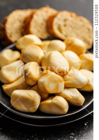 Smoked mini scamorza cheese. Traditional italian cheese on plate on black table. 112329588