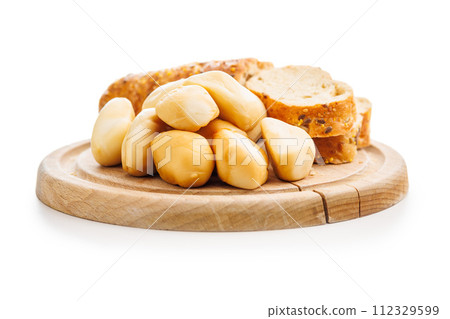 Smoked mini scamorza cheese. Traditional italian cheese on cutting board isolated on white background. Smoked mini scamorza cheese. Traditional italian cheese on cutting board isolated on white background. 112329599