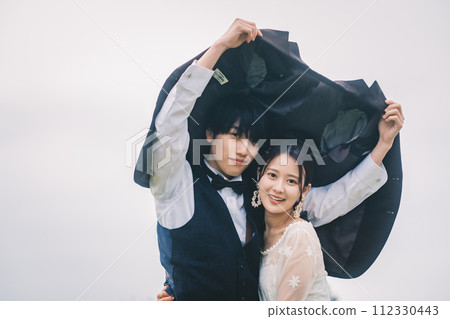 Man and woman cuddling outdoors in the rain 112330443