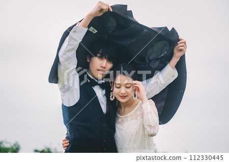 Man and woman cuddling outdoors in the rain 112330445