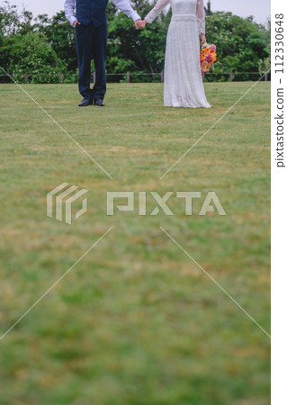 Bride and groom holding hands in the park 112330648
