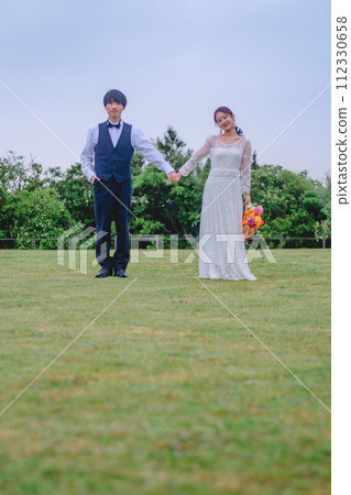 Bride and groom holding hands in the park 112330658