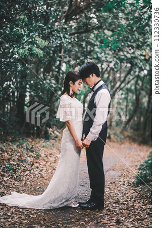 Bride and groom facing each other in the forest Bride and groom facing each other in the forest 112330736