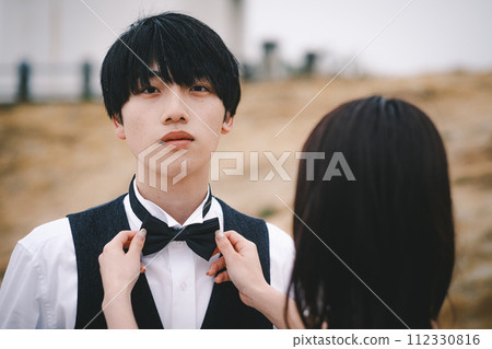 Groom getting his bride to tie his tie Groom getting his bride to tie his tie 112330816