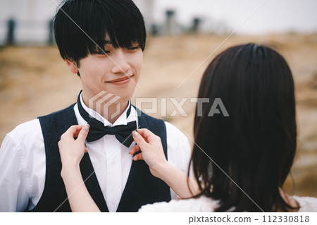 Groom getting his bride to tie his tie 112330818