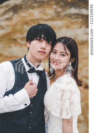 Bride and groom cuddling on a rock Bride and groom cuddling on a rock 112330846