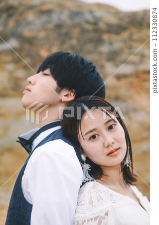 Bride and groom standing back to back on a rock Bride and groom standing back to back on a rock 112330874