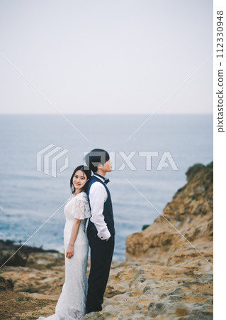 bride and groom cuddling on the beach 112330948