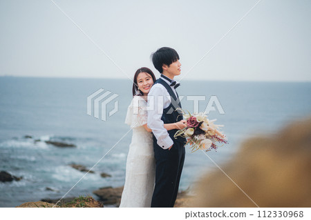 bride and groom cuddling on the beach 112330968