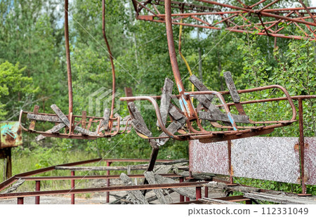 Eerie scene of an abandoned amusement park: a rusting merry-go-round overtaken by nature Eerie scene of an abandoned amusement park: a rusting merry-go-round overtaken by nature 112331049