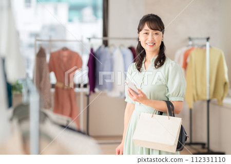 一位中年婦女在商店購物時操作智能手機 112331110