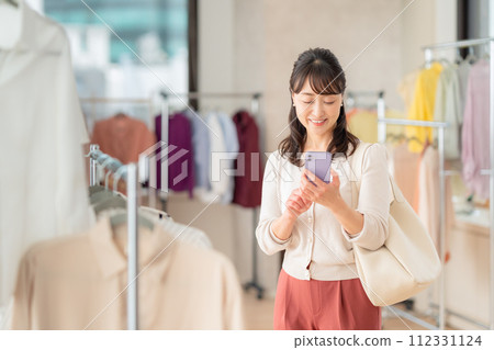 A middle-aged woman operating a smartphone while shopping at a store 112331124