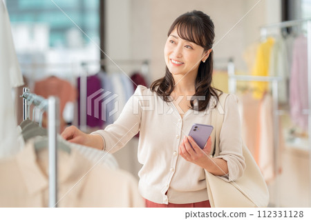 A middle-aged woman operating a smartphone while shopping at a store 112331128