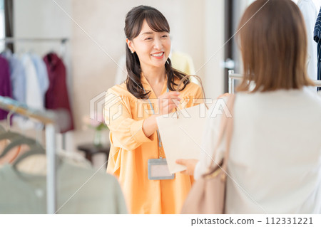 A middle-aged female clerk working at an apparel shop A middle-aged female clerk working at an apparel shop 112331221
