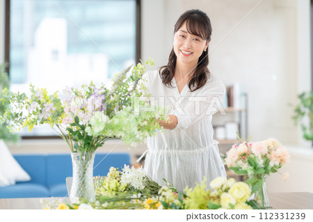 A middle-aged woman who makes a hobby flower arrangement in the living room A middle-aged woman who makes a hobby flower arrangement in the living room 112331239