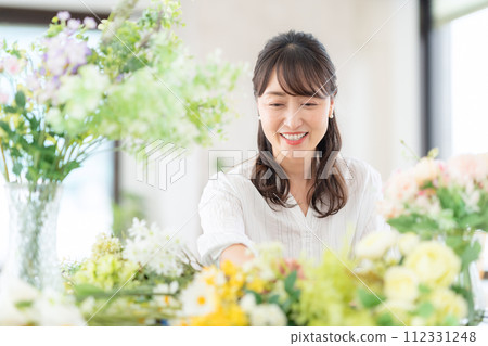 A middle-aged woman who makes a hobby flower arrangement in the living room 112331248