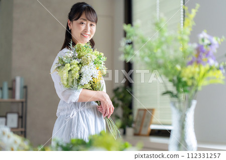 A middle-aged woman who makes a hobby flower arrangement in the living room 112331257