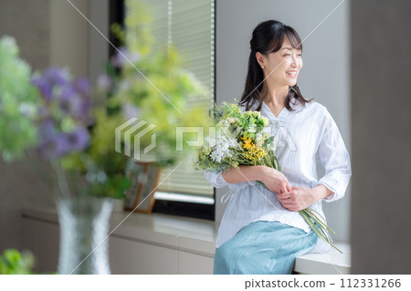 A middle-aged woman who makes a hobby flower arrangement in the living room A middle-aged woman who makes a hobby flower arrangement in the living room 112331266