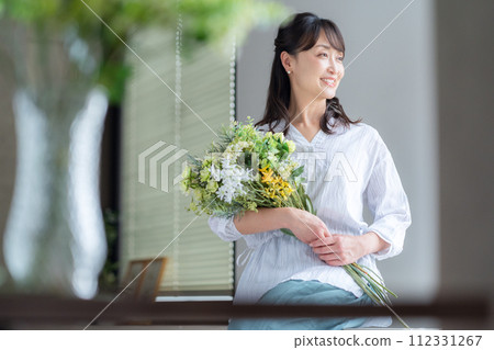 A middle-aged woman who makes a hobby flower arrangement in the living room A middle-aged woman who makes a hobby flower arrangement in the living room 112331267