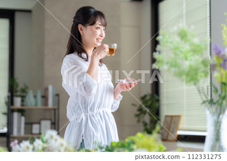客廳窗邊喝茶的中年婦女 112331275