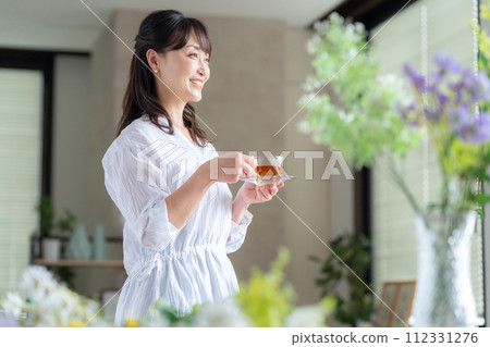 Middle-aged woman drinking tea by the window in the living room 112331276