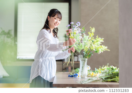 A middle-aged woman who makes a hobby flower arrangement in the living room A middle-aged woman who makes a hobby flower arrangement in the living room 112331283