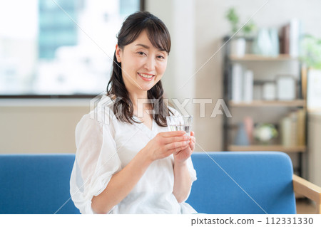 Middle-aged woman drinking water in the living room 112331330