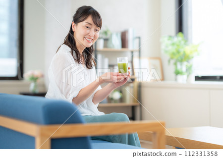 中年婦女在客廳喝綠汁 中年婦女在客廳喝綠汁 112331358