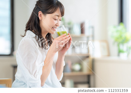 中年婦女在客廳喝綠汁 中年婦女在客廳喝綠汁 112331359