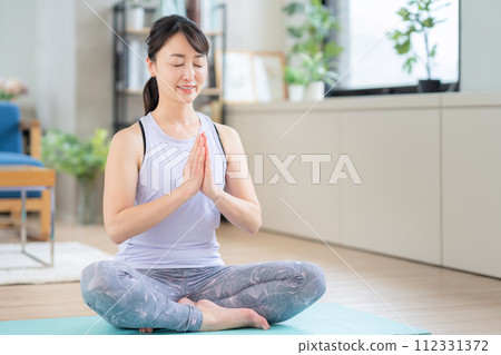 Middle-aged woman doing yoga in the living room Middle-aged woman doing yoga in the living room 112331372
