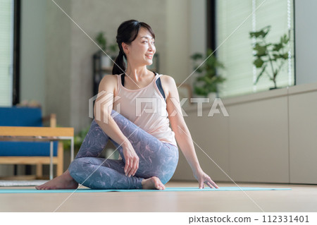 Middle-aged woman doing yoga in the living room 112331401