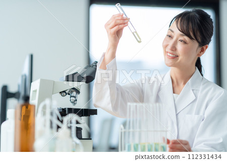 一位中年婦女在顯微鏡下進行研究和實驗 一位中年婦女在顯微鏡下進行研究和實驗 112331434