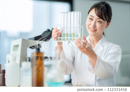 A middle-aged woman looking into a microscope for research and experiments A middle-aged woman looking into a microscope for research and experiments 112331438