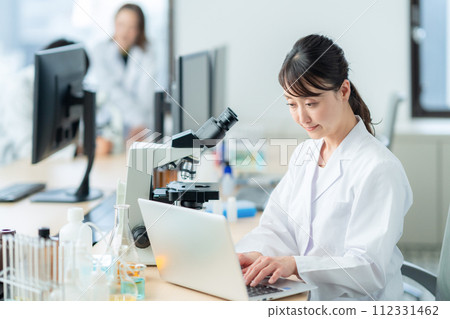 A middle-aged woman looking into a microscope for research and experiments 112331462