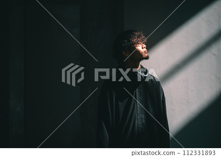 man standing in front of a wall with light man standing in front of a wall with light 112331893