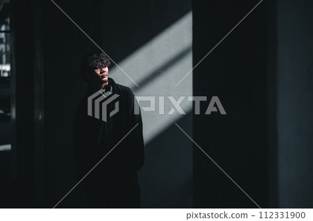 man standing in front of a wall with light man standing in front of a wall with light 112331900